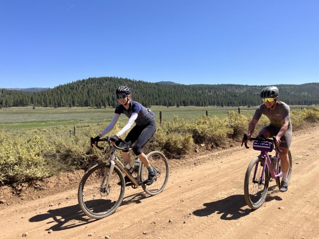 Two gravel cyclists riding through the Sierra Valley meadow on a clear day