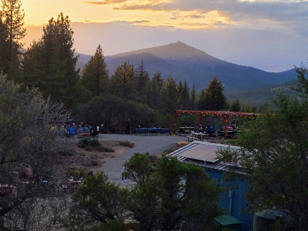 Sunset view of High Camp deck with string lights and mountain backdrop during the Gravel Social