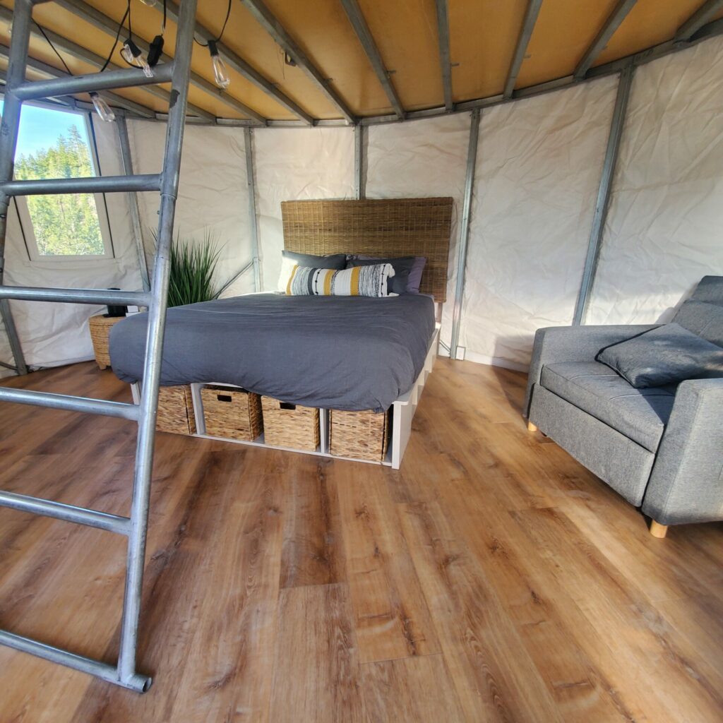 Interior of the High Camp yurt with queen bed and ladder to the loft